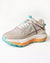 Beige running shoe with blue and orange sole on a white background